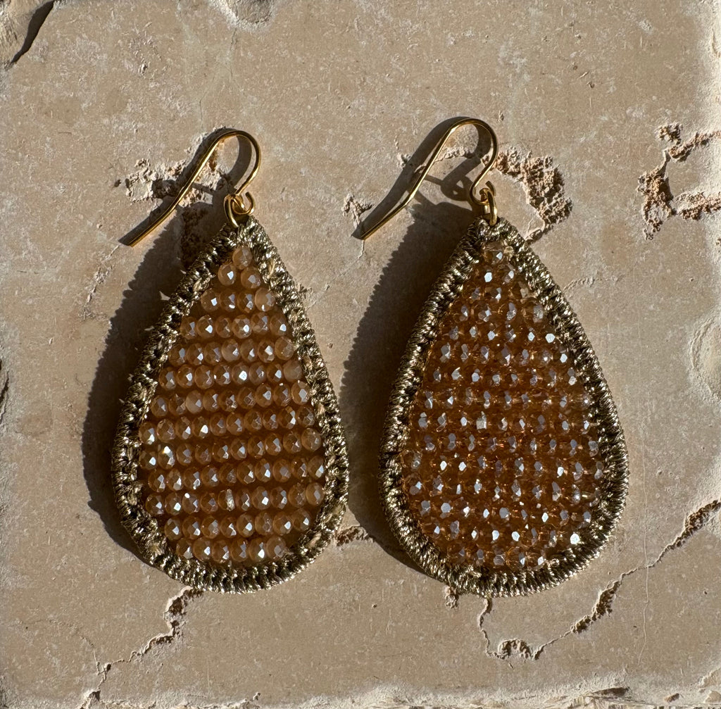 Champagne crystal teardrop earrings flat lay on stone