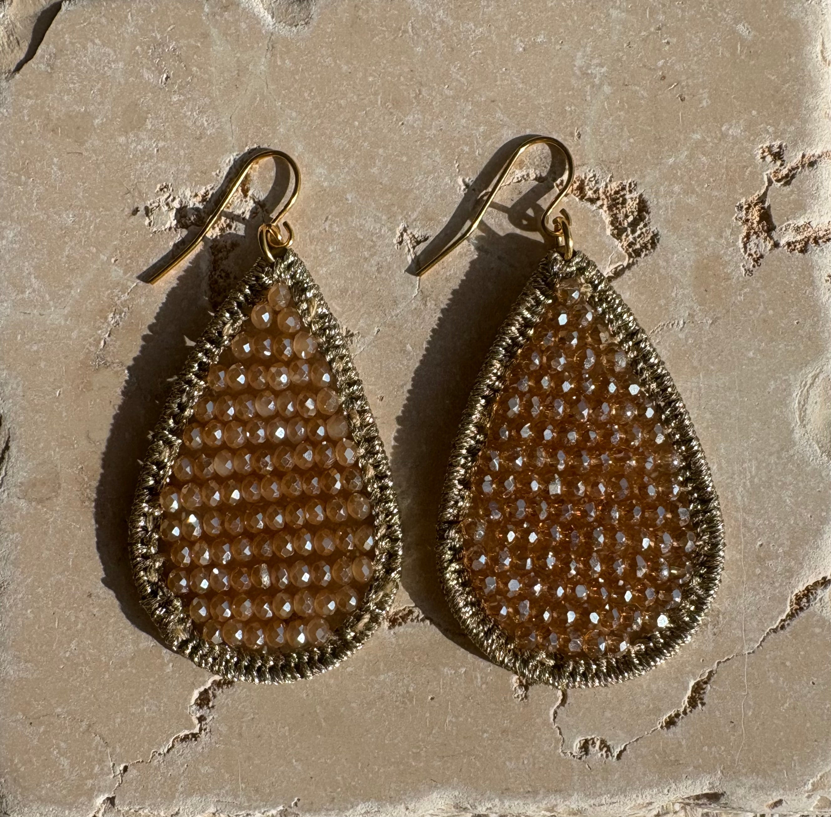 Champagne crystal teardrop earrings flat lay on stone