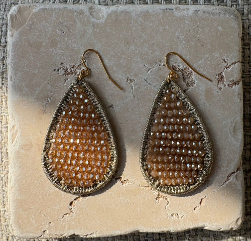 Champagne crystal teardrop earrings flat lay on marble tile