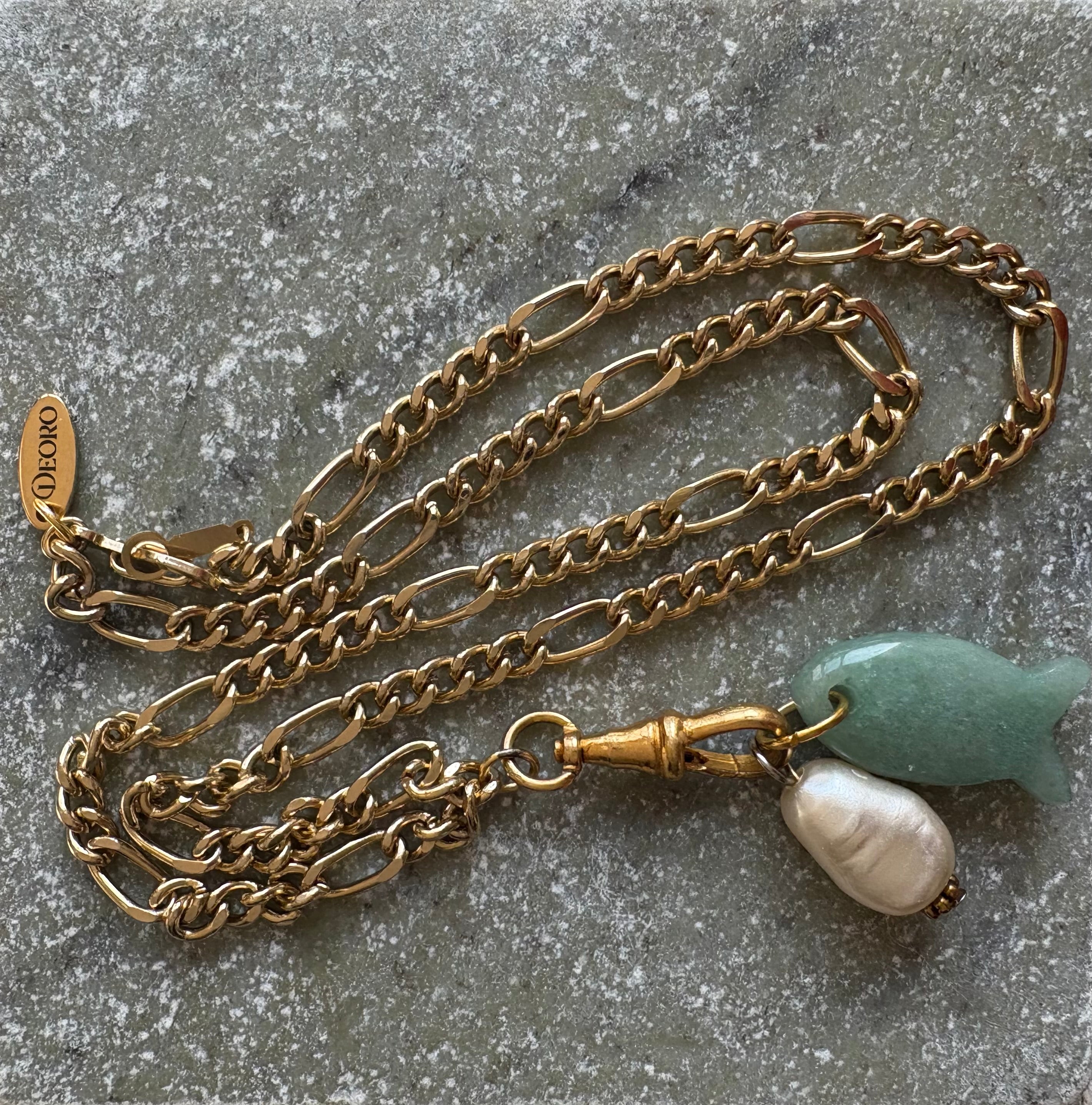 Gold figaro chain necklace flat lay with Deoro tag