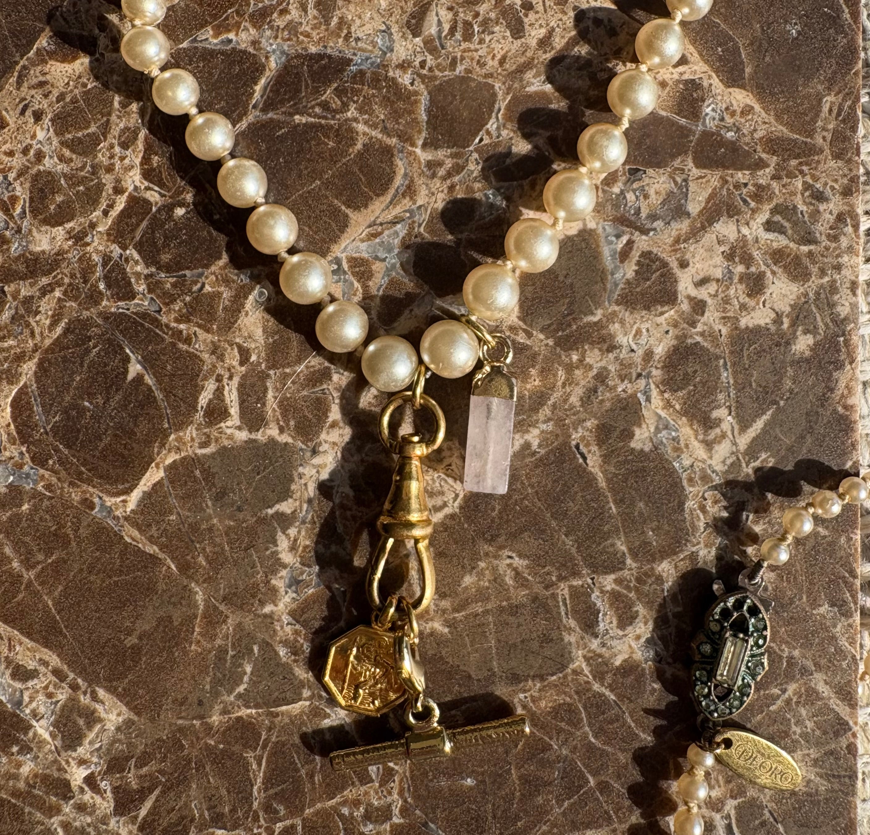 Vintage pearl necklace with gold charms on marble - detail